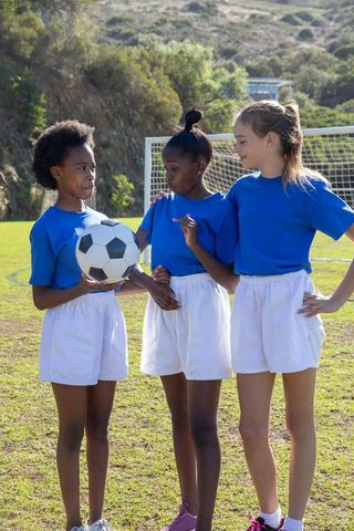 Diverse Girls Discussing Soccer Tactics on Field