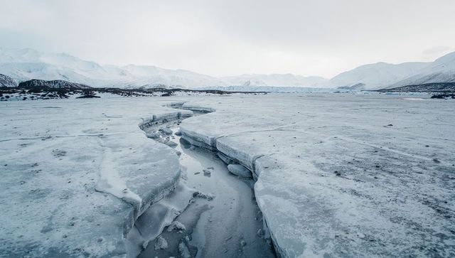 Revealing glacial ice fissure running toward horizon on frozen arctic plain
