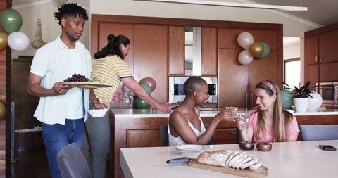 Friends Celebrating in Modern Kitchen with Food and Drinks