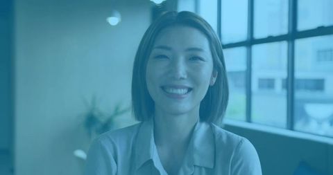 Smiling Asian Woman in Modern Office Lounge with Natural Light