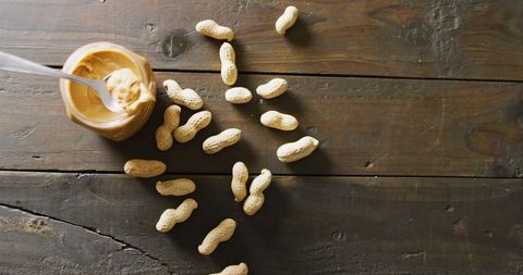 Peanut butter jar with whole peanuts on wooden table