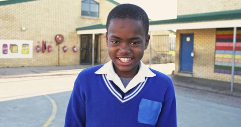 Happy schoolboy smiling outside school building