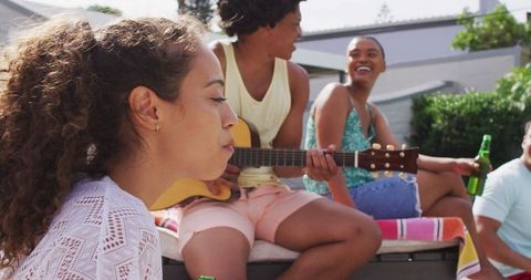 Young friends laughing and singing at casual garden party