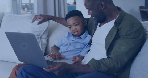Father and Son Bonding Over Laptop on Comfortable Sofa