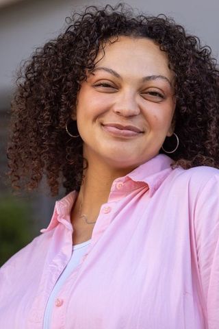 Confident african american woman smiling in pink shirt with silver hoop earrings