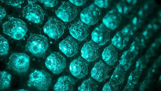 Teal faceted lens array emitting glowing led light, honeycomb optics macro abstract