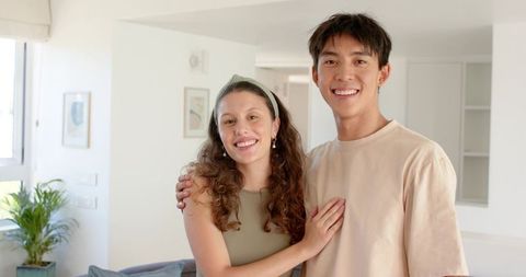 Young couple smiling in bright minimalist living room embracing warm cozy home vibe