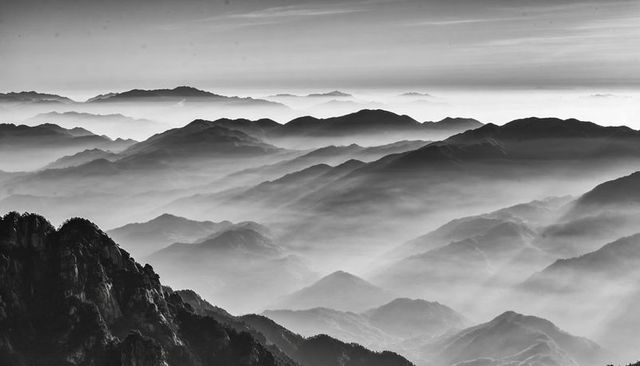 Layering mist-filled mountain ridges creating serene monochrome panoramic wilderness vista