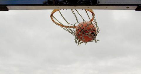 Basketball Swishing Through Hoop Against Sky