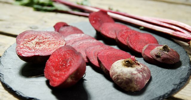 Sliced beets are artistically arranged on a slate board, showcasing their vibrant red interior, with copy space. Beets are a nutritious root vegetable known for their earthy flavor and health benefits.