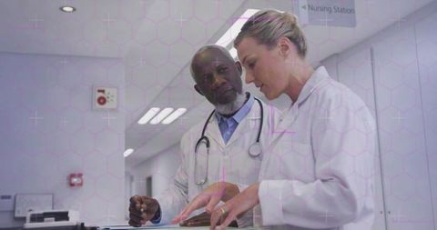 Doctors collaborating over patient chart in hospital corridor reviewing clinical documentation