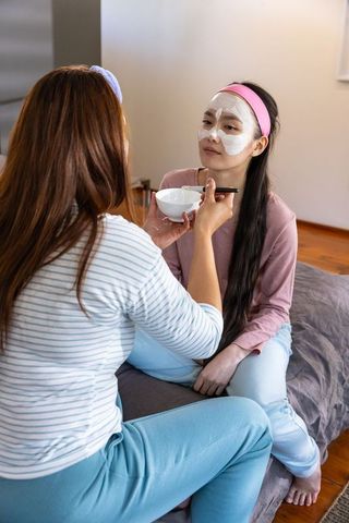 Diverse Friends Enjoying Skincare Routine with Facial Masks in Bedroom