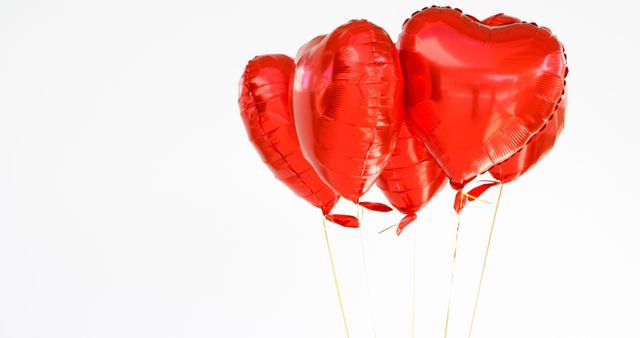 Red heart-shaped balloons against a white background are floating together. Perfect for celebrating love-filled holidays like Valentine's Day, anniversaries, or romantic events. Ideal for use in greeting cards, party invitations, decorations, and social media posts related to love and romance.