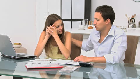 Couple Anxiously Reviewing Expenses and Budget at Office Desk