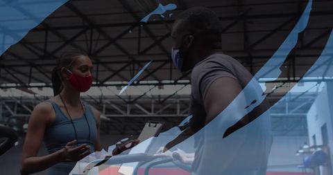 Fitness trainers discussing workout plans with masks in gym