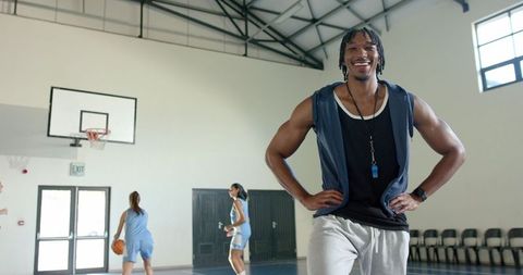 Smiling basketball coach inspiring women athletes in gym