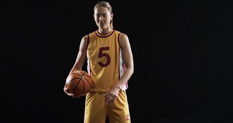 Confident Female Basketball Player Posing with Ball on Black Background