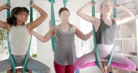 Diverse Women Practicing Aerial Yoga for Wellness Enhancement