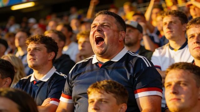 Passionate sports fan shouting and cheering in sunlit stadium stands during match