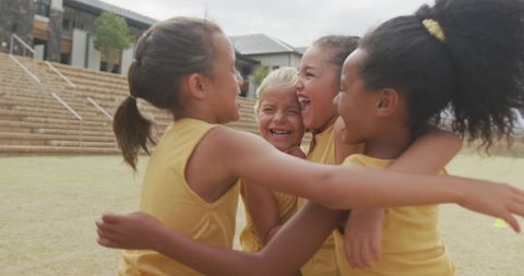Joyful Diverse Schoolgirls Celebrating with Hugs on Sports Field