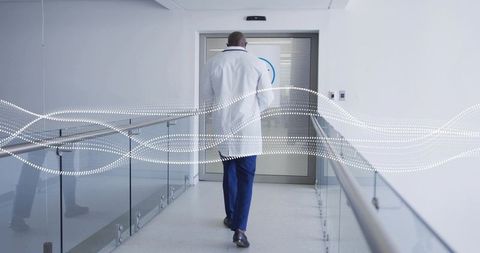 Walking physician in white coat and blue scrubs along hospital corridor with digital wave