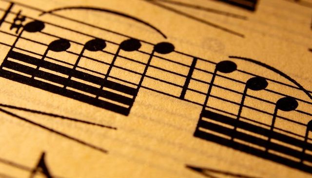 Vintage sheet music close-up macro of beamed notes and slurs on yellowed paper