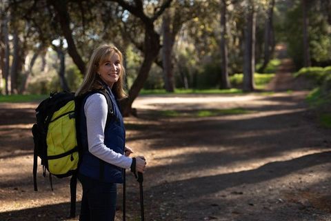 Woman Hiking on Forest Trail With Trekking Poles and Backpack