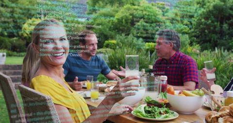 Multigenerational family enjoying alfresco dinner in backyard with code overlay hinting digital life