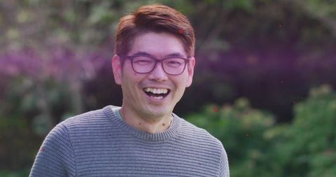 Joyful Mature Asian Man Smiling Outdoors in Greenery