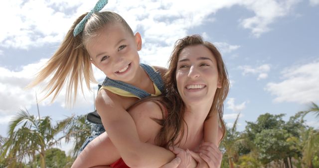 Mother giving daughter piggyback ride outdoors on sunny day - Download Free Stock Images Pikwizard.com