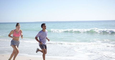 Young Individuals Enjoying Jogging on Sunny Beach