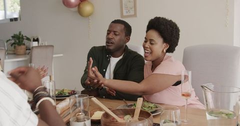 Joyful african american couple sharing laughter at dining table