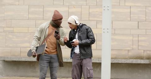 Two Friends Sharing Music and Skateboard in Urban Winter Streetwear