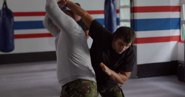 Men practicing self-defense moves in martial arts class wearing gym attire. Use for articles on fitness, self-defense techniques, martial arts classes, or training blogs.
