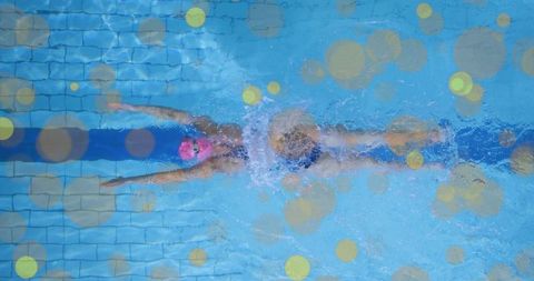 Overhead freestyle swimmer gliding through lane with pink cap and goggles for training