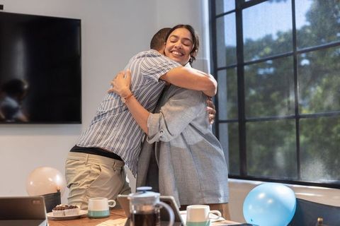 Diverse Female Colleagues Embracing at Office Celebration