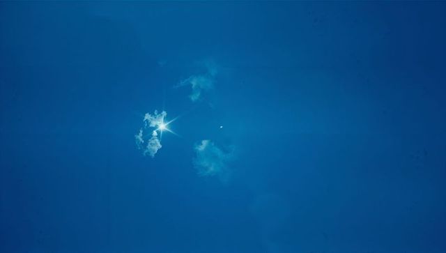 Starburst Sun in Deep Blue Sky with Wispy Clouds