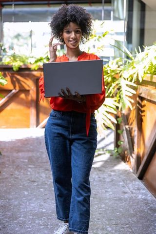 Confident African American Woman Holding Laptop on Urban Balcony