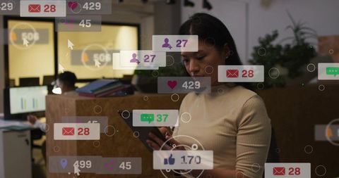 Woman checking mobile notifications in open-plan office with social media icons