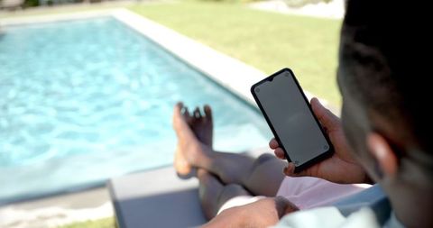 Man Relaxing by Swimming Pool Browsing Smartphone in Leisure Time