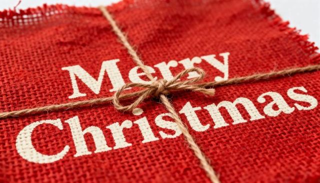 Rustic red burlap merry christmas gift wrap featuring jute twine bow, closeup texture