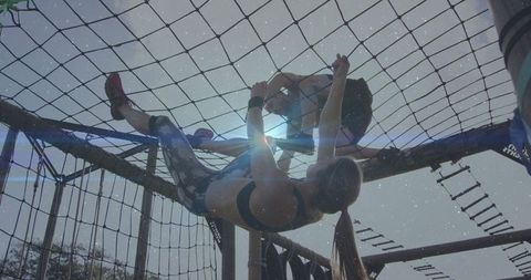 Duo Climbing on Obstacle Course Net Demonstrating Teamwork and Strength