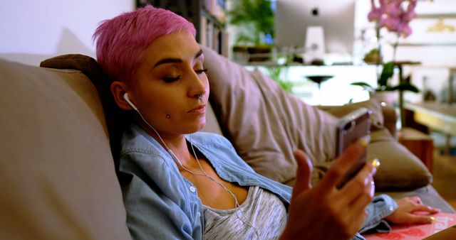 Young Woman with Pink Hair Relaxing on Couch While Listening to Music on Smartphone - Download Free Stock Images Pikwizard.com