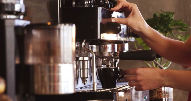 Hand is operating an espresso machine, making coffee. Ideal for illustrating barista jobs, coffee house themes, or promotions for coffee brewing equipment.