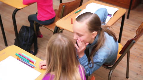 Two Girls Whispering Secrets During Class
