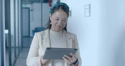 Professional Asian Woman Using Tablet in Modern Office Corridor