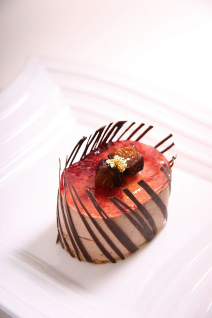 Gourmet chocolate mousse cake on an elegant white plate, garnished with figs and gold leaf. This sophisticated dessert is perfect for upscale culinary presentations, bakery advertisements, food blogs, and fine dining menus.