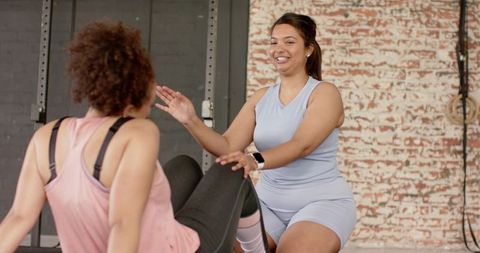 Female trainer guiding partner core workout in industrial gym, coaching and motivation