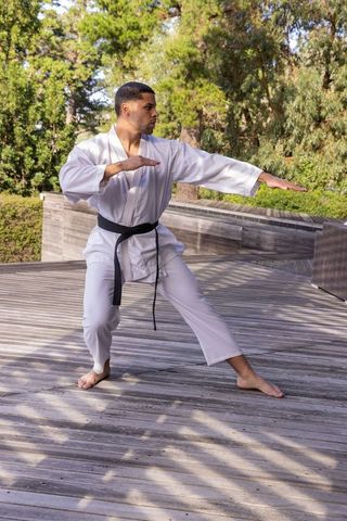 Karate Practitioner in Traditional Gi on Wooden Deck in Outdoor Setting