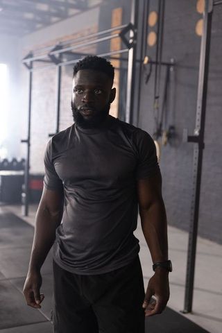 African american man standing in industrial gym wearing fitted shirt and shorts, post-workout focus